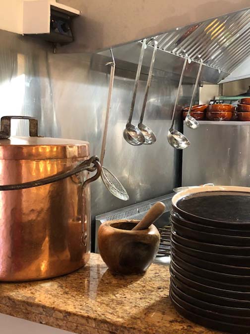 Photo de la cuisine du restaurant avec une marmite en cuivre en premier plan